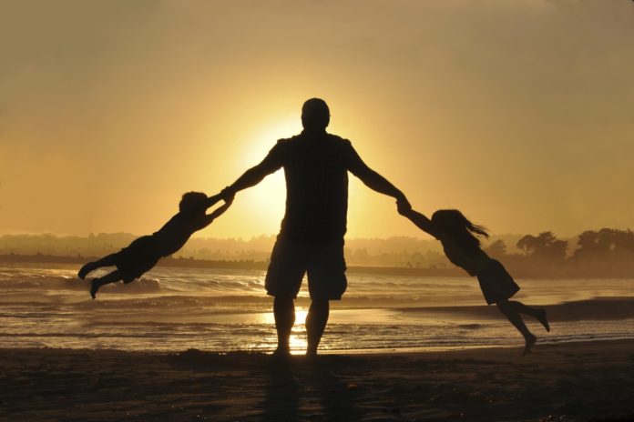 Un père jouant avec ses enfants à la plage