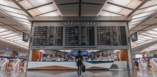 Une passagère consultant un guide de voyage sur un écran, dans un aéroport.