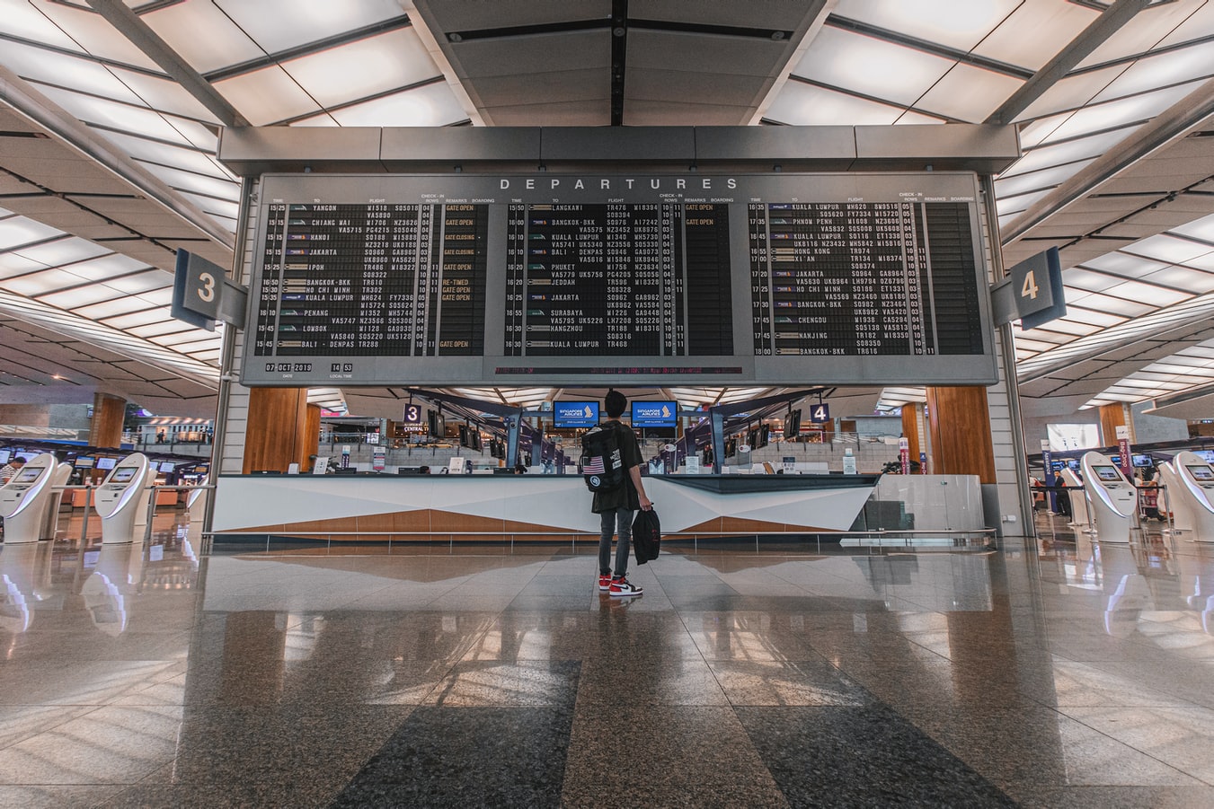 Une passagère consultant un guide de voyage sur un écran, dans un aéroport.