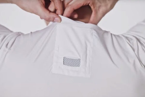 Un mannequin rangeant le climatiseur portable Reon Pocket dans le cou, dans le t-shirt spécial.